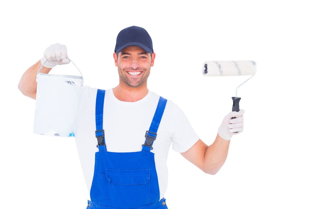 Portrait of smiling handyman with paint can and roller on white background